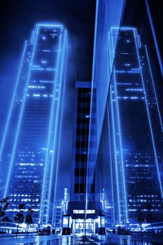 two tall buildings lit up at night in the city