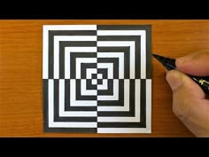 someone is drawing a black and white square in the middle of a wooden table with a pen