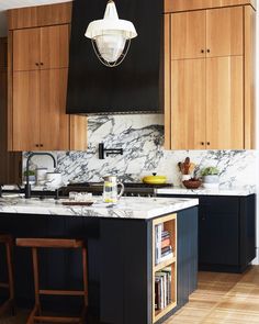 a kitchen with wooden cabinets and marble counter tops, along with an island in the middle