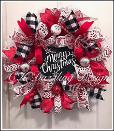 a red and black christmas wreath on a door with the words merry christmas written on it