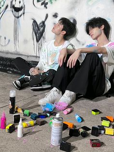 two young men sitting on the ground next to graffiti