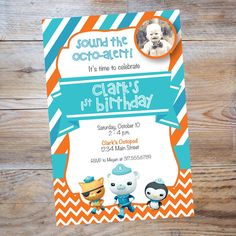 an orange and blue birthday party card with two little cartoon characters on it, sitting on top of a wooden table