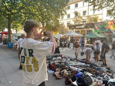 a young man standing in front of a pile of shoes on the ground next to people