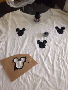 a white shirt with mickey mouse cut outs on it and some glue sitting next to it