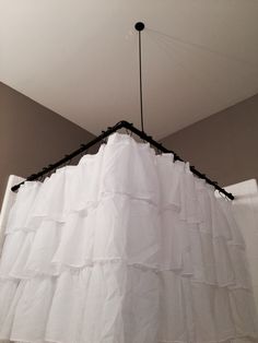 a white curtain hanging from the ceiling in a room with a light fixture above it