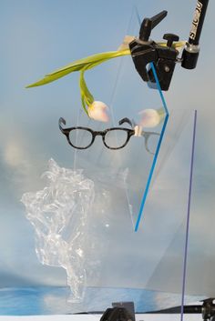 a pair of eyeglasses hanging from the side of a glass display case in front of a blue sky