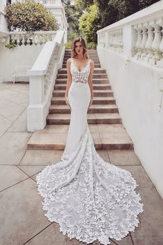 a woman in a wedding dress standing on the steps with her hands behind her back