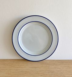 a white and blue plate sitting on top of a wooden table next to a wall