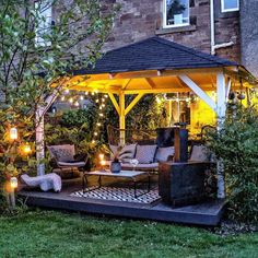 a gazebo is lit up with lights in the evening for an outdoor seating area