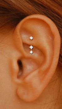 a woman's ear with three diamond studs