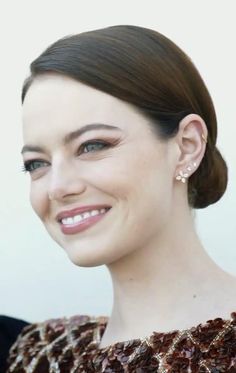 a close up of a person with a smile on their face and hair in a bun