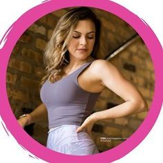 a woman with her hand on her hip in front of a brick wall and pink circle