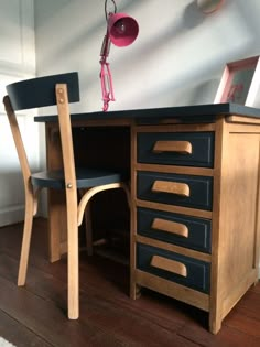 a wooden desk with two chairs and a pink lamp on it's headlamp