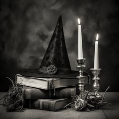 a stack of books sitting next to a candle on top of a wooden table in front of a black and white background