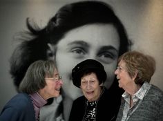 three women standing next to each other in front of a wall with an image of a woman