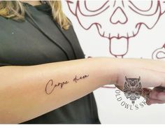 a person with a small owl tattoo on their arm that says carpo alumi