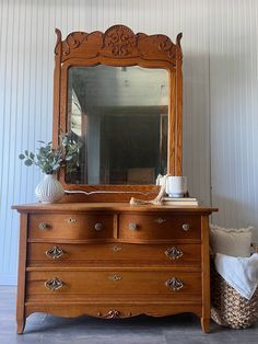 an old dresser with a mirror and vase on top