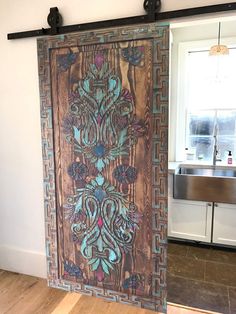 a wooden door with an intricate design painted on the front and side panels, in a kitchen