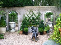 an outdoor garden with potted plants and statues in the center, surrounded by stone arches