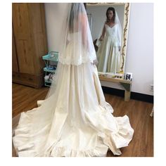 a woman in a wedding dress looking at herself in the mirror with her veil pulled back