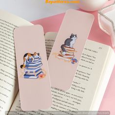 two bookmarks with cats sitting on top of books