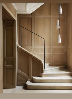 an elegant staircase with wooden paneling and white marble steps leading up to the second floor