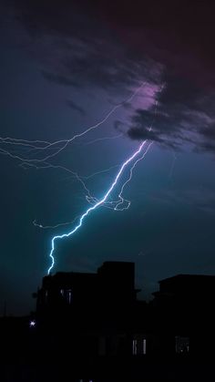 lightning strikes in the night sky over some buildings