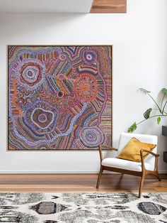 a large painting hanging on the wall above a chair in a room with a rug