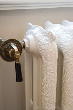 an ornate white radiator with brass knobs on it's side and a black handle