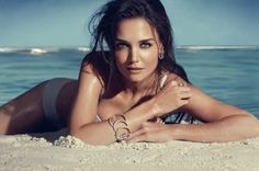 a beautiful woman laying on top of a sandy beach