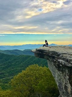 a person sitting on top of a cliff