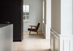 a chair sitting in the middle of a room next to a wall with white trim