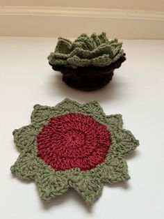 two crocheted flower coasters sitting on top of a white table next to each other