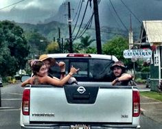 two people sitting in the back of a pick up truck giving thumbs up to someone