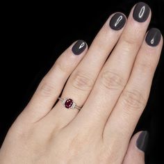 a woman's hand with a ring on it and a red stone in the middle