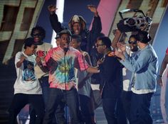 a group of young men standing on top of a stage with microphones in their hands