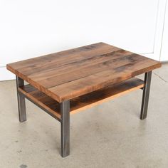 a wooden table with metal legs in front of a white wall