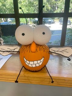 a pumpkin with googly eyes sitting on top of a table