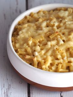 a bowl filled with macaroni and cheese on top of a white wooden table