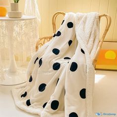 a white and black polka dot blanket sitting on top of a chair next to a table