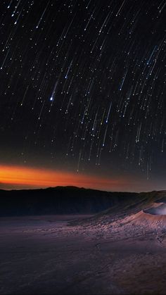 the night sky is filled with stars as it shines brightly over a desert landscape