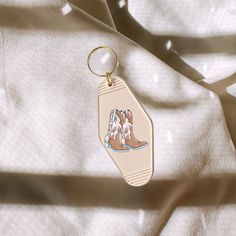 a keychain with two horses on it sitting on a white cloth covered surface