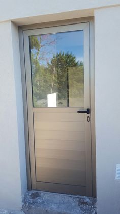 the front door to a house with a glass window on it's side and trees in the background