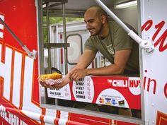 a man holding a hot dog on top of a red and white truck