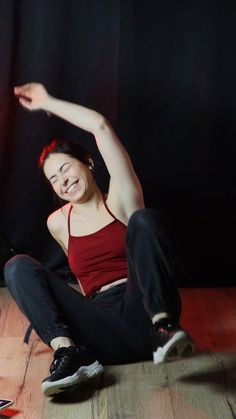 a woman is sitting on the floor with her arms in the air and she is smiling