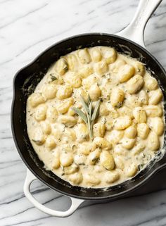 a skillet filled with macaroni and cheese on top of a marble counter