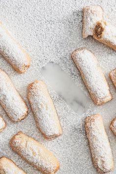 powdered sugar covered pastries are arranged on a white tablecloth and scattered around them