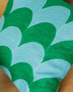 a green and white pillow sitting on top of a wooden table