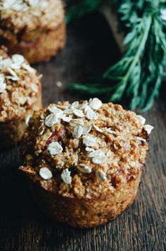 two muffins with oats are sitting on a table next to a pine branch