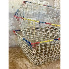 two wire baskets sitting on top of a stone floor next to each other with handles